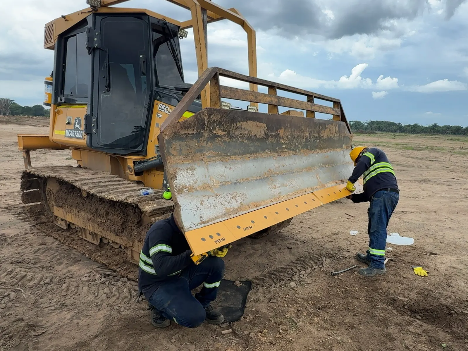 Técnicos de LN Equipos ajustando la cuchilla de un bulldozer John Deere 650J en campo